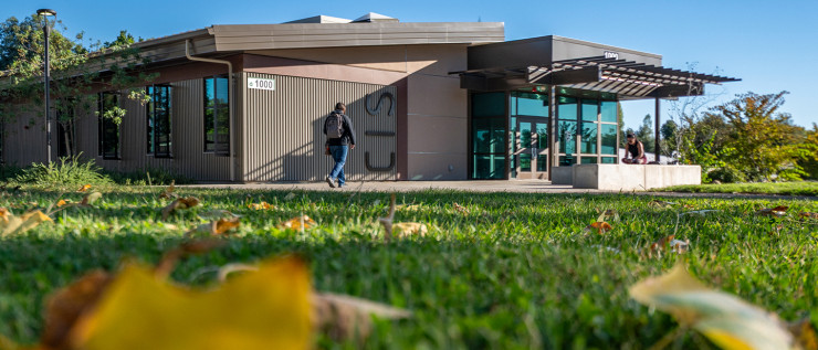 Modern Shasta College building with large windows, surrounded by trees with autumn leaves