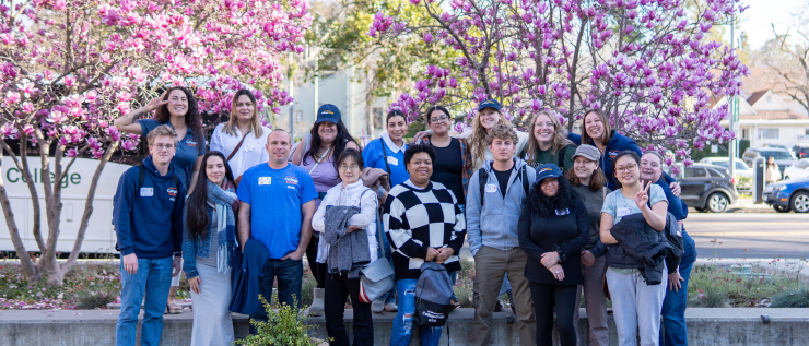 Group of students standing in front of blooming trees on campus