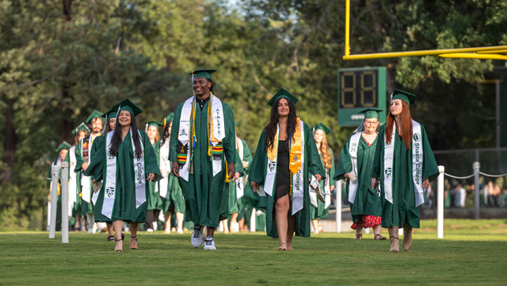 Student walking on a field in their commencement regalia 