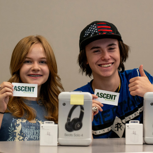 Two smiling students holding up Ascent cards